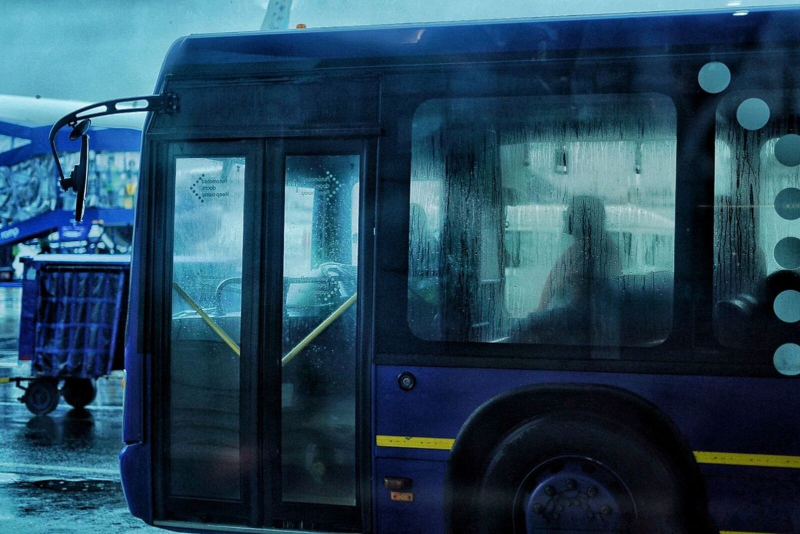 Airport bus on the apron beside a jet bridge