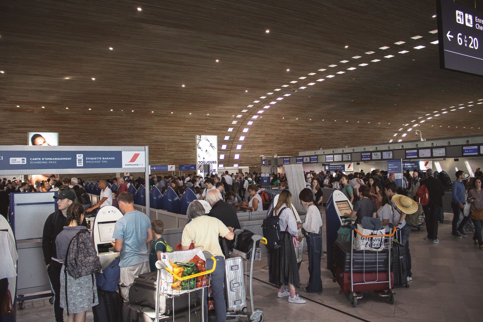 Busy airport departures hall with travellers and luggage trolleys