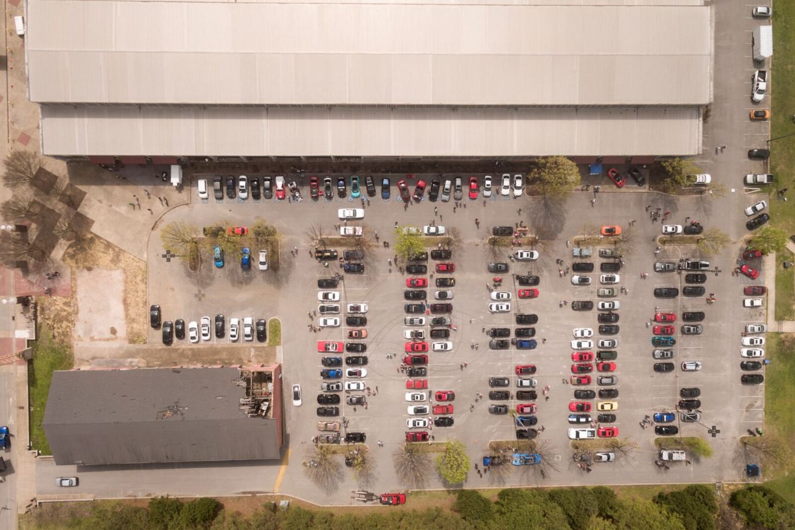 Aerial view of an open-air car park beside a large building