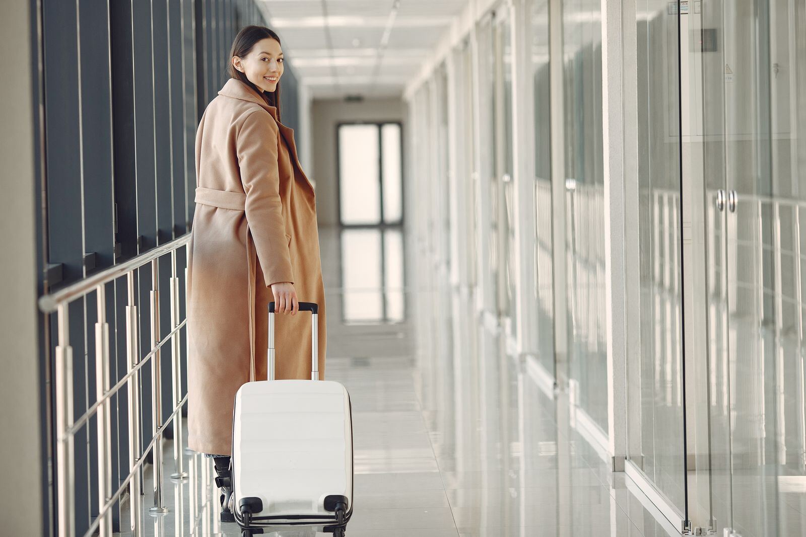 Smiling traveller with a suitcase in an airport corridor